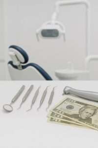 Dental equipment on table with money with a dental chair in background